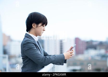 Geschäftsfrau, die ein Smartphone bedient Stockfoto