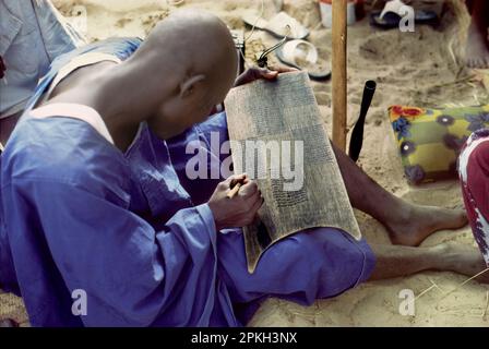 Afrika, Tschad, Sahelzone, Tschadinseln: Kanembu-Mann, der den Koran studiert, Verse auf einer hölzernen Tafel schreibt. Stockfoto