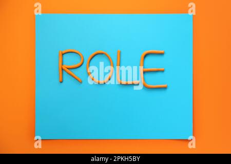 Wortrolle aus Plastik auf orangefarbenem Hintergrund, flach liegend Stockfoto