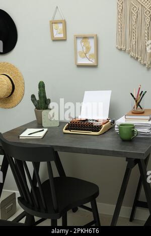 Schreibmaschine und Papierstapel auf dunklem Tisch im Zimmer. Schreibarbeitsplatz Stockfoto