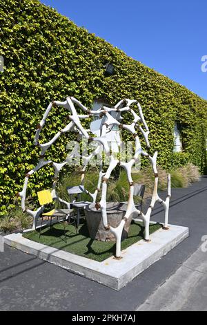 COSTA MESA, KALIFORNIEN - 4. April 2023: Dinosaurier-Skelett-Skulptur mit Tisch und Stühlen im LABOR Anti Mall. Stockfoto