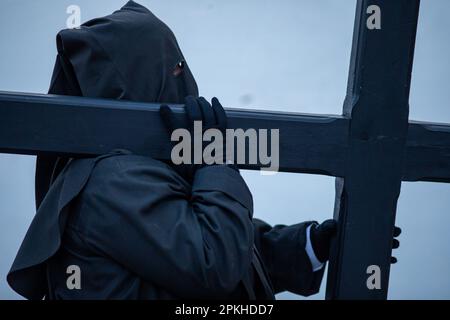 Sahagun, Spanien. 07. April 2023. Ein Bußgesicht trägt ein hölzernes Kreuz auf seinen Schultern, während der Heiligen Begräbnisprozession, die durch die Straßen von Sahagun ging. Kredit: SOPA Images Limited/Alamy Live News Stockfoto
