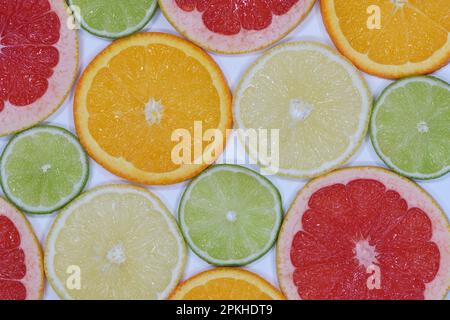 Eine flache Draufsicht mit einer Auswahl an glänzenden, frischen, saftigen Orange-, Limonen-, Grapefruit-, Und Zitronenscheiben in hellem Licht, aufgenommen in einem Studio Stockfoto