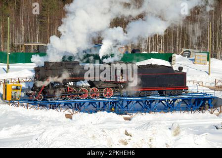 RUSKEALA, RUSSLAND - 10. MÄRZ 2021: Die alte sowjetische Dampflokomotive L-2198 dreht sich an einem sonnigen Märztag in einem Wendekreis. Karelien Stockfoto