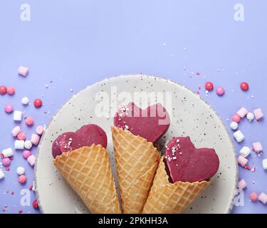 Violettes Heidelbeer-Eis auf lilafarbenem Hintergrund. Stimmungsvolles, süßes Menükonzept. Draufsicht, flach liegend, Kopierbereich Stockfoto