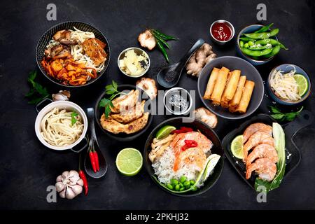 Verschiedene asiatische Gerichte auf schwarzem Hintergrund, Draufsicht. Asiatisches Speisenkonzept. Stockfoto