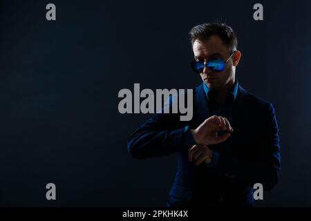 Porträt eines attraktiven, fröhlichen Gentleman, der isoliert vor dunklem Hintergrund posiert Stockfoto