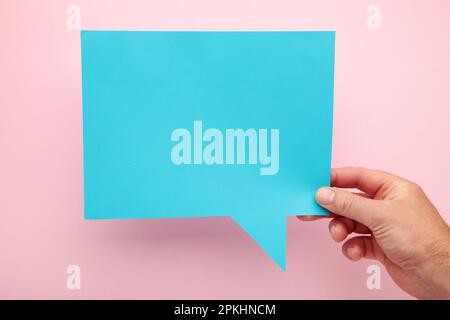 Hand mit einer blauen Sprechblase auf pinkfarbenem Hintergrund. Draufsicht Stockfoto