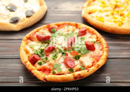 Drei verschiedene Pizzasorten auf einem braunen Holztisch mit Kopierbereich. Draufsicht Stockfoto