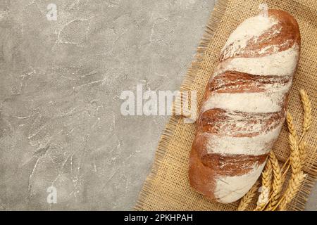 Vollkornbrot auf Sacktuch auf grauem Hintergrund. Draufsicht Stockfoto