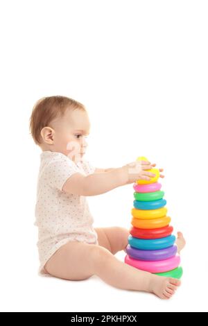 Niedliches Baby, das mit der bunten Regenbogenpyramide auf weißem Hintergrund spielt. Kind mit pädagogischem Spielzeug. Draufsicht Stockfoto