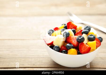 Obstsalat in einer Schüssel mit Gabel, serviert auf dem Tisch. Draufsicht Stockfoto
