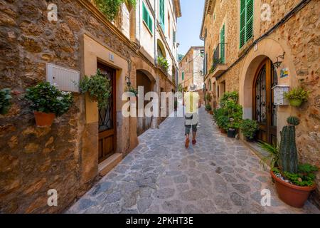 Häuser mit Blumentöpfen dekoriert, Touristen in einer Gasse mit typischen Steinhäusern, Valldemossa, Serra de Tramuntana, Mallorca, Balearen, Spanien Stockfoto