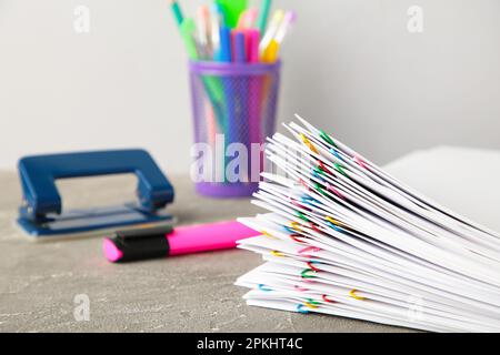 Weißes Papier mit mehrfarbigen Clips und Schreibwaren auf Grau. Draufsicht Stockfoto