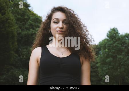 Porträt einer schönen jungen Frau mit braunem, langen Locken in der Natur Stockfoto