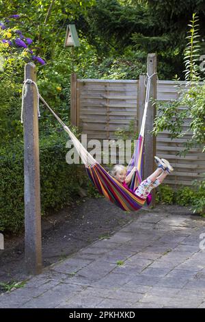 Mädchen (8) in Hängematte im Garten, Kiel, Schleswig-Holstein, Deutschland Stockfoto