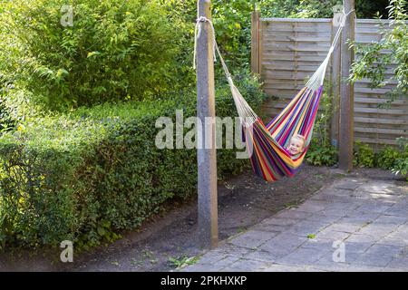 Mädchen (8) in Hängematte im Garten, Kiel, Schleswig-Holstein, Deutschland Stockfoto