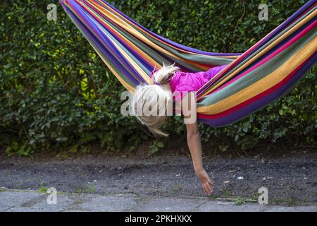 Mädchen (8) in Hängematte im Garten, Kiel, Schleswig-Holstein, Deutschland Stockfoto