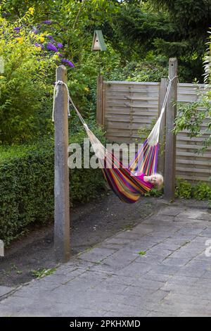 Mädchen (8) in Hängematte im Garten, Kiel, Schleswig-Holstein, Deutschland Stockfoto