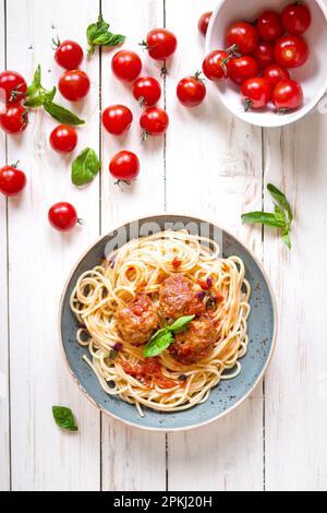 Köstliche Spaghetti mit hackbällchen und Tomatensauce auf einem Teller. Serviert auf einem weißen rustikalen Holztisch. Ein italienisch-amerikanische Gericht. Ansicht von oben Stockfoto