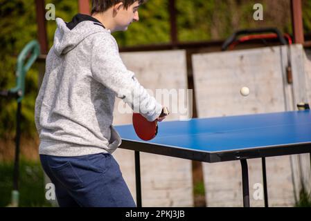 Ein Teenager spielt Tischtennis in seinem Garten Stockfoto