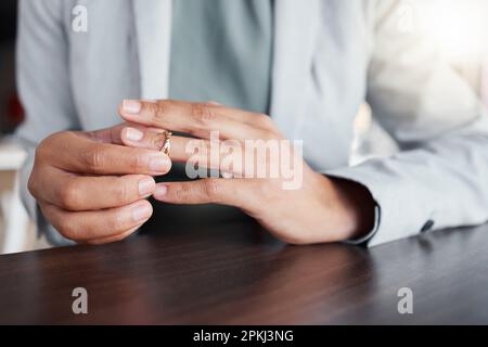 Finger, Scheidung und Ring an der Hand einer Frau am Tisch mit Zweifel, Angst und Depression im Haus. Weibliche Person, die Hochzeitsband-Schmuck abnimmt Stockfoto