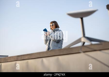 Die Frau benutzt Starlink Internet auf dem Dach Stockfoto