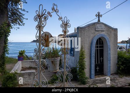 Blaue Kapelle mit Kreuz und Engel auf dem Dach, erbaut in einem wunderschönen kleinen Garten an der Küste. Kinira, Insel Thassos (Tassos), Griechenland. Stockfoto