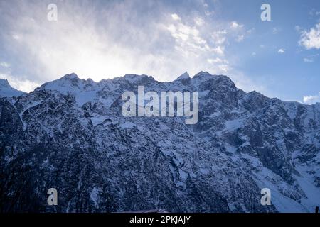 Schneebedeckte Berge des himalaya mit Nadelbäumen vor dem Haus und ein blauer verschneiter Himmel, der manali, lahaul, spiti und leh Touristenattraktionen zeigt Stockfoto