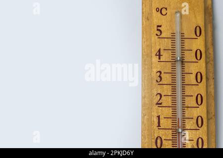 Raumthermometer auf einem Holzsockel, Nahaufnahme auf weißem Hintergrund. Grad Celsius. Stockfoto