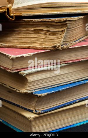 Ein Stapel von Büchern mit festem Einband und dunklem Hintergrund. Bücherregal, Wissensliteratur, Literatur. Buchhandlung Buchhandlung. Stockfoto