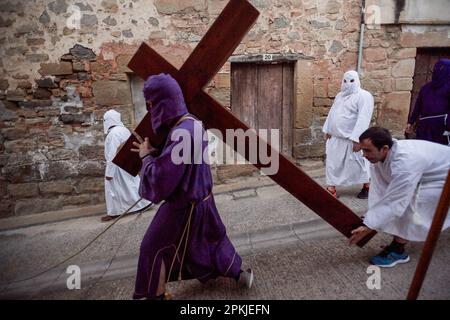 Eine Reue der Bruderschaft der „Santa de la Vera Cruz“, transportiert das Kreuz Jesu Christi, begleitet von einer anderen Reue, die die Stille der Prozession bricht, indem sie es während der Feier des Karfreitags in der Stadt Torres del Río, Navarra, Spanien, trifft. Die Bruderschaft der 'Santa de la Vera Cruz' feiert eine charakteristische Prozession in der Heiligen Woche in Torres del Río, Navarra, Spanien, in der die Bußgesellen weiß gekleidet sind und einen kleinen Teil des Camino de Santiago, In dem sie ein Kreuz tragen, in dem ein Buße die Stille der Nacht bricht, indem er zum Klang schlägt Stockfoto