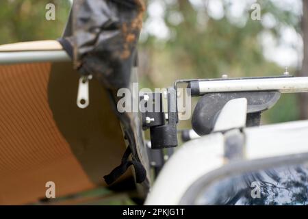 Nahaufnahmen einer verlängerten seitlichen Markise, die an einem Dachgepäckträger befestigt ist, mit Schnellverschlüssen, die ein einfaches Entfernen ermöglichen, wenn sie nicht verwendet wird. Stockfoto