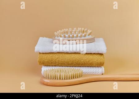 Bürsten und Handtücher für natürliche Bambusmassagen. Massagebürste mit Naturborsten auf einem Frottee-Handtuch. Heim-SPA-Konzept, Selbstpflege. Stockfoto