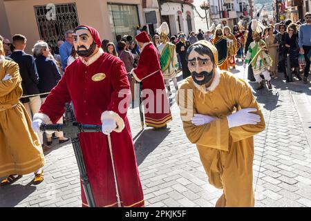 Puente Genil, Spanien. 07. April 2023. Eine biblische Figur in Gelb, die den „Juden“ repräsentiert, versucht, während einer Karfreitagsprozession, die Teil der Heiligen Woche ist, vor seinem römischen Sklaven wegzulaufen, oder Semana Santa, 7. April 2023 in Puente Genil, Spanien. Die Stadt hat eine ungewöhnliche Feier mit einer Prozession aller biblischen Figuren seit 1661. Kredit: Richard Ellis/Richard Ellis/Alamy Live News Stockfoto