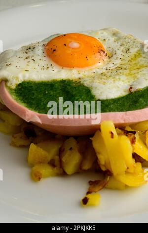 Gebratenes Ei auf Spinat in einer Wurstschüssel und gebratene Kartoffeln nach österreichischer Art Stockfoto