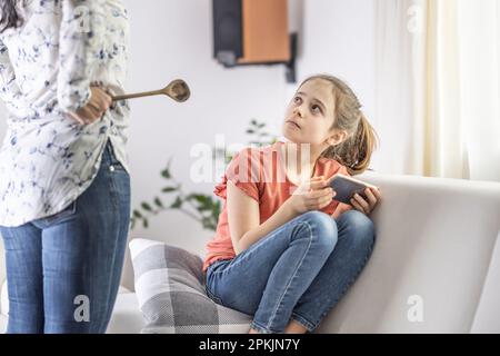 Mutter-Tochter-Unstimmigkeit mit strenger Mutter, die ihr mitteilt, dass sie die ganze Zeit online ist. Stockfoto