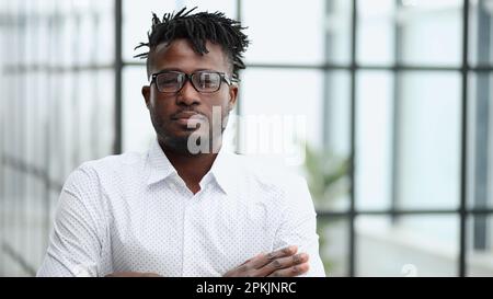 Kopfschuss Porträt von einem jungen afrikanischen Mann mit Brille, der in die Kamera schaut Stockfoto
