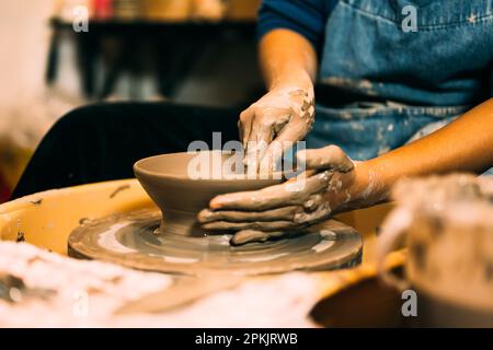Handwerker, die Töpferkännchen aus Lehm auf Töpferrad in der Werkstatt herstellen Stockfoto