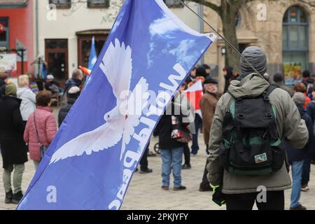 Jena, Deutschland. 08. April 2023. Ein Teilnehmer an einem ostermarsch steht mit einer Flagge, die eine Taube des Friedens während einer Kundgebung am Holzmarkt darstellt. Im Jahr 2023 fanden auch zahlreiche Ostermärsche in ganz Deutschland unter dem Eindruck von Russlands Krieg gegen die Ukraine statt. Kredit: Bodo Schackow/dpa/Alamy Live News Stockfoto