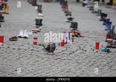 Jena, Deutschland. 08. April 2023. Eine Taube läuft an Kinderschuhen vorbei auf einem Platz im Zentrum der Stadt. Mit der Aktion sammeln Frauen, die aus der Ukraine geflohen sind, Spenden für die Eltern von Kindern, die im Krieg getötet wurden. Kredit: Bodo Schackow/dpa/Alamy Live News Stockfoto