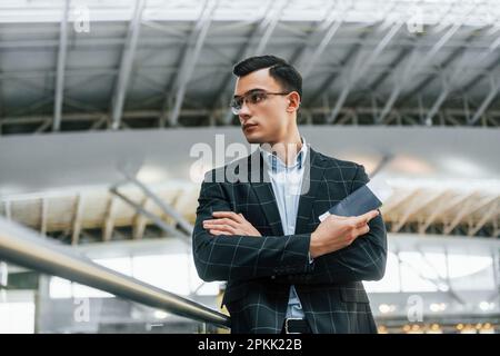 Seriöser Look. Ein junger Geschäftsmann in formeller Kleidung ist tagsüber im Flughafen Stockfoto