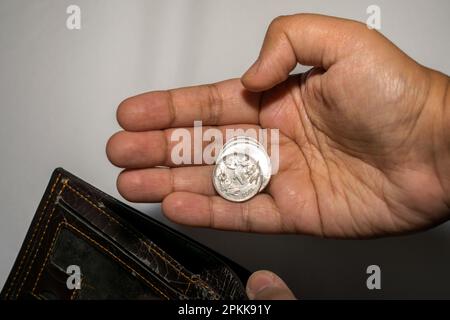 Eine Geschäftsfrau, die ein paar indische Rupien-Münzen in der Hand hat, arbeitslos und bankrott, schaut in ihre leere Brieftasche Stockfoto