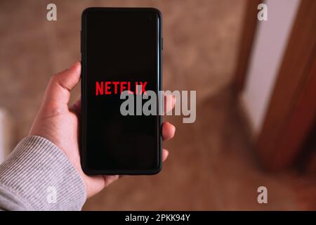 Málaga – SPANIEN – 6. APRIL 2023: Frau streamt Netflix auf Smartphone. Digitale Geräte. App mobil. Netflix und entspann dich. Stockfoto