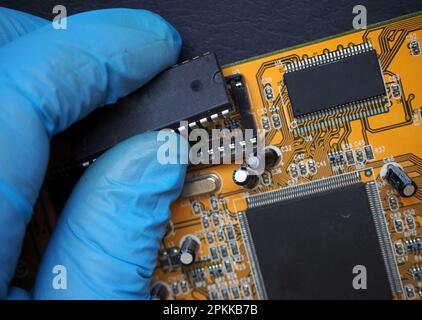 28-poliger integrierter Schaltkreis aus Sockel auf der Hauptplatine entfernt. Chip, der in die Buchse auf der elektronischen Leiterplatte gesteckt wird. Stockfoto