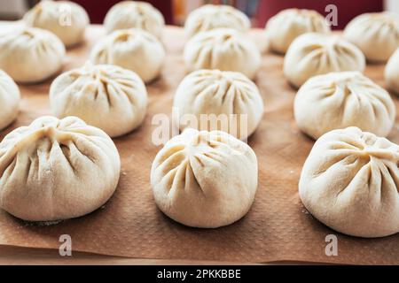 Eine Gruppe von bao wird auf einen Tisch gestellt und wartet darauf, gedünstet zu werden. Bao, auch bekannt als Baozi. Es ist traditionelles chinesisches Essen. Stockfoto