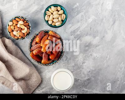 Ramadan Kareem – Speisen und Getränke. Getrocknete Datteln, Nüsse und Milch auf grauem Hintergrund. Islamische Religion und ramadan-Konzept. Draufsicht. Speicherplatz kopieren Stockfoto