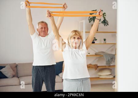 Dehnübungen und Fitnessübungen. Seniorenmann und -Frau sind zu Hause zusammen. Stockfoto