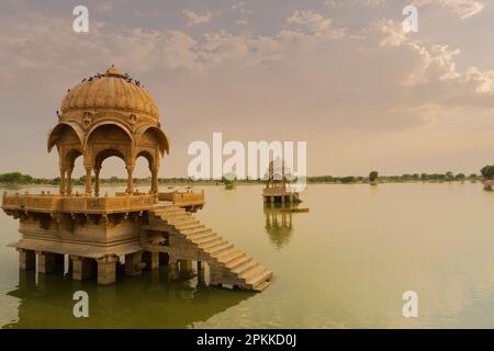 Chhatris und Schreine der hinduistischen Götter und Göttinnen am Gadisar-See, Jaisalmer, Rajasthan, Indien mit Reflexion über Wasser. Indoislamische Architektur. Stockfoto