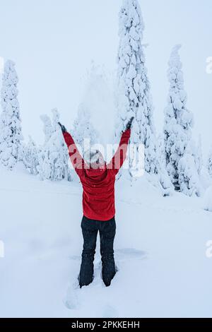 Fröhliche Frau mit ausgestreckten Armen, die mit Schnee spielt, Lappland, Finnland, Europa Stockfoto